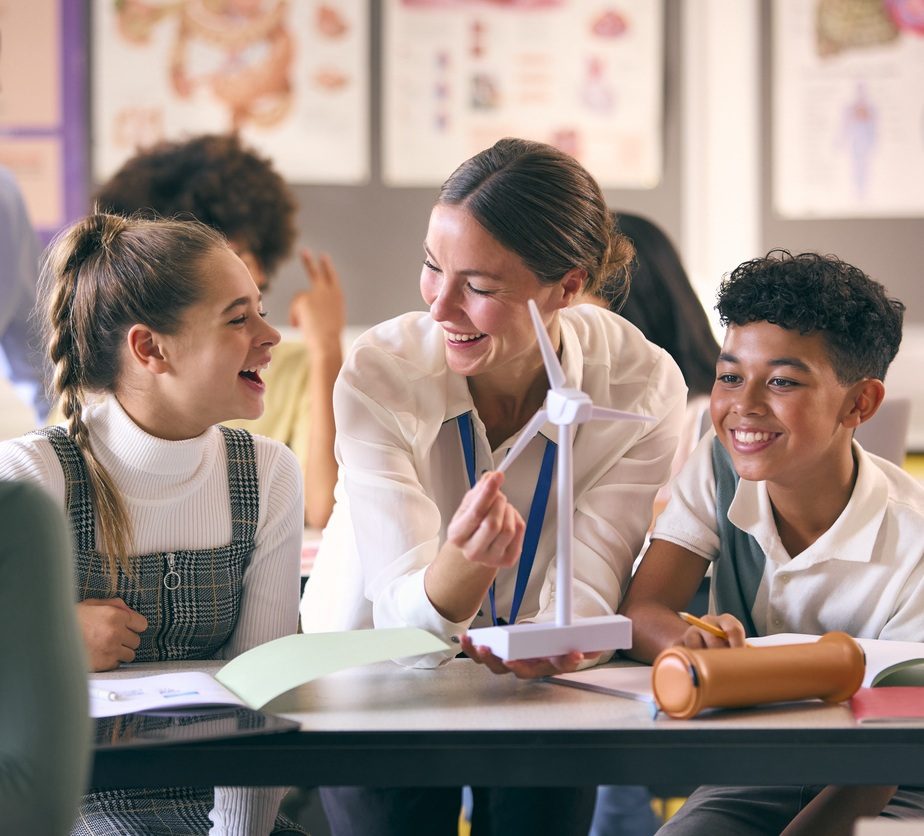 A teacher guiding students through a hands-on classroom lesson