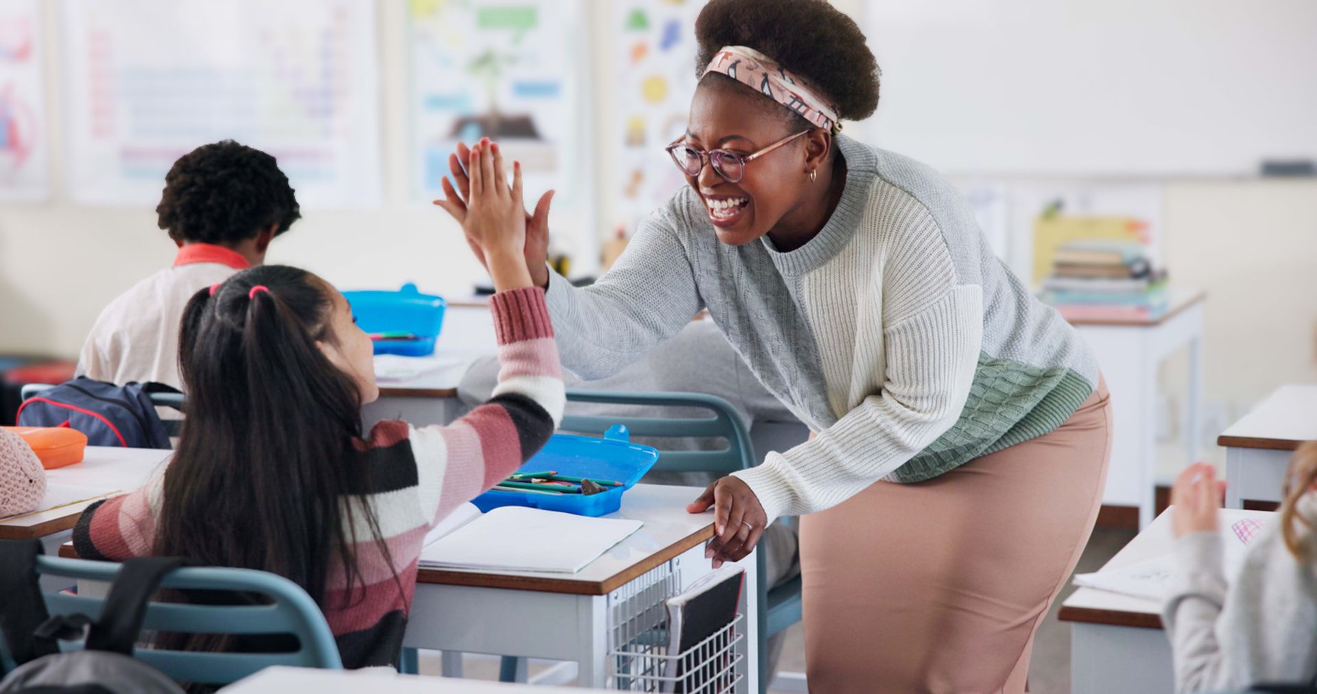 A teacher and a student sharing a high five in a classroom